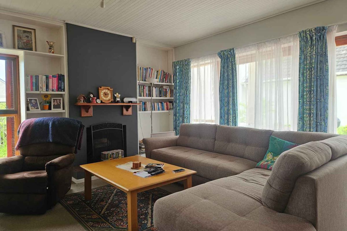 A comfortable living room featuring a fireplace with a mantelpiece, built-in shelving units, and large windows allowing for natural light.