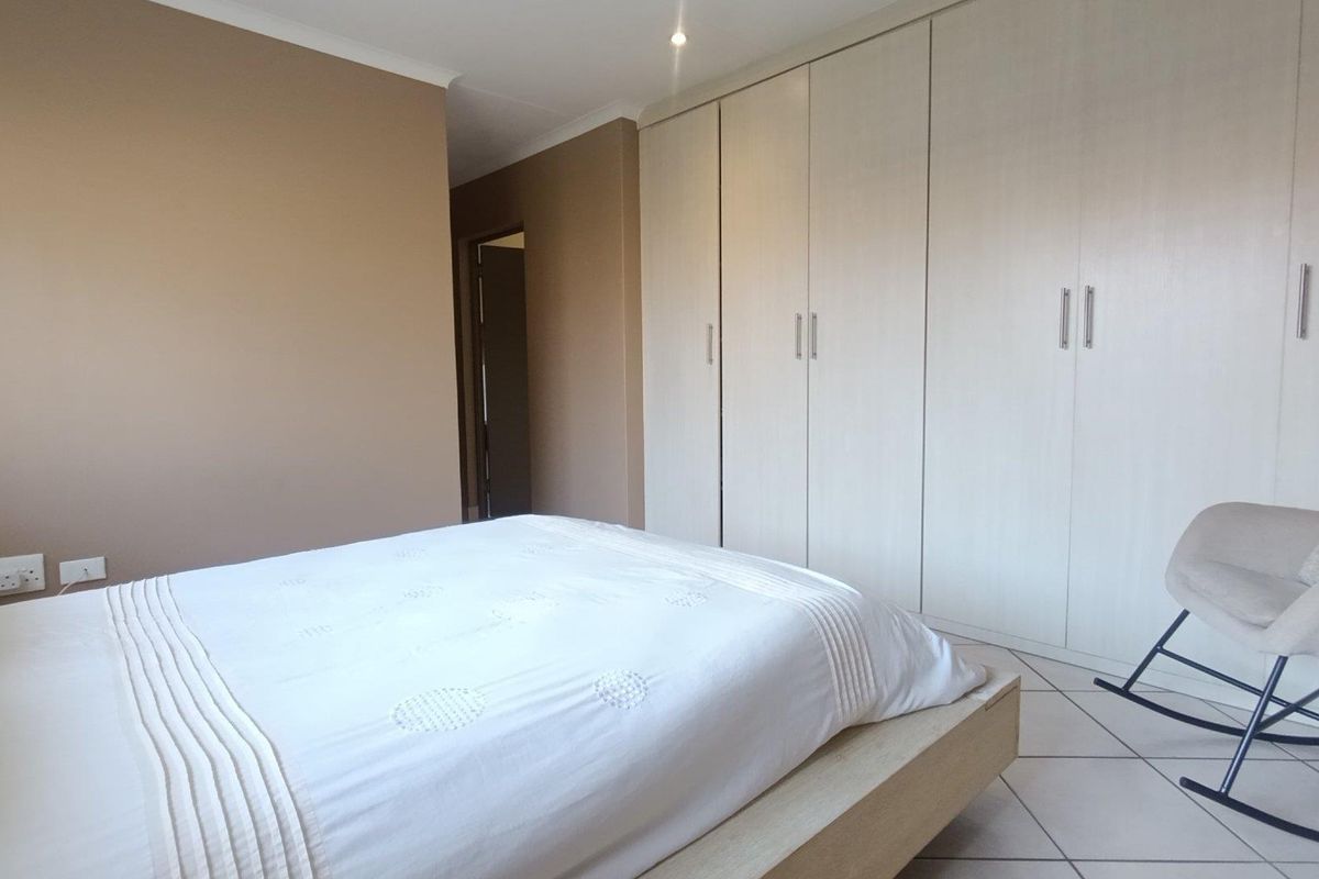A well-maintained bedroom featuring neutral wall tones, tiled flooring, and extensive built-in cabinetry providing ample storage space.
