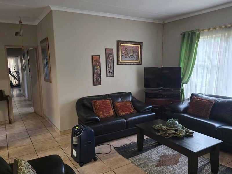 A living room featuring tiled flooring and cove cornicing, providing a functional and neutral space for relaxation.
