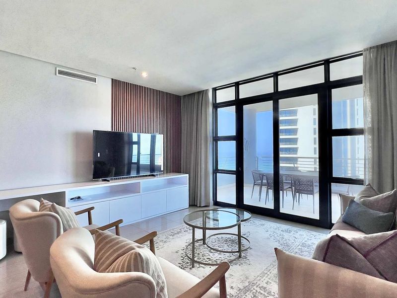 Modern living room featuring a sleek built-in media console, decorative slatted timber wall paneling, and large sliding glass doors opening to a balcony.
