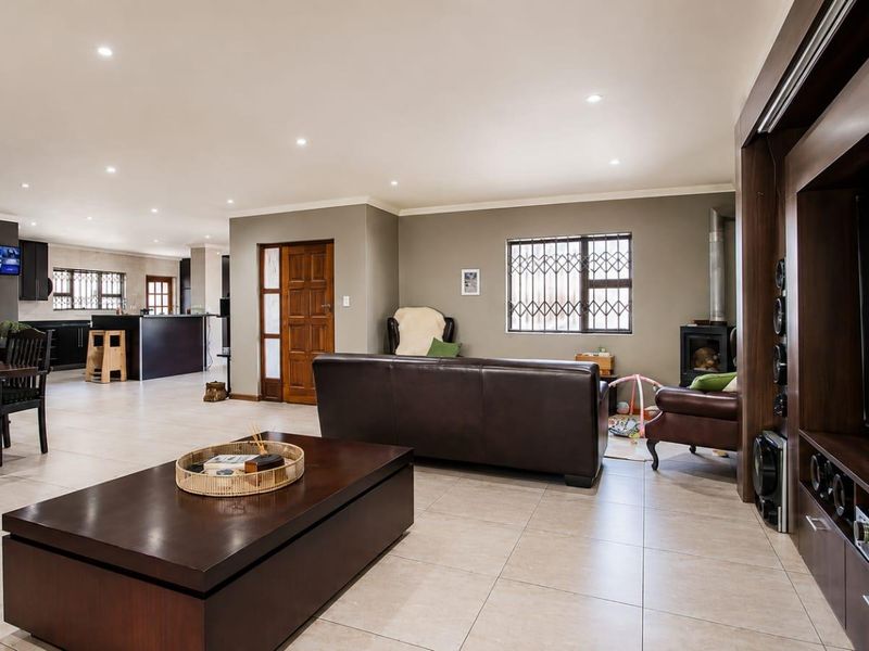 Spacious open-plan living area featuring tiled floors, recessed lighting, a built-in fireplace, and a modern kitchen with a central island.