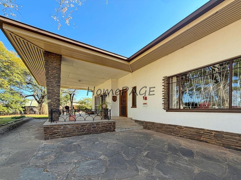 Front facade of a house featuring a covered patio, stone cladding accents, and flagstone paving.