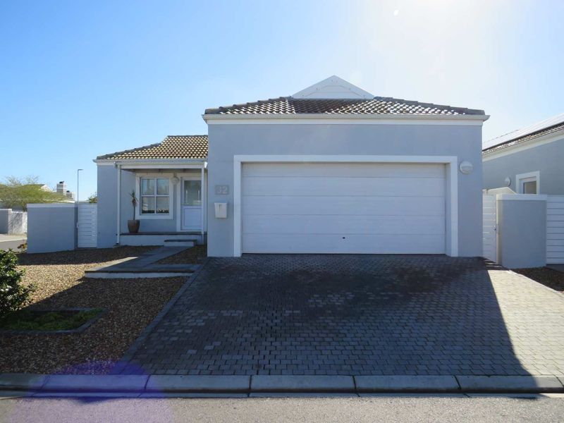 Front elevation of a single-story residential property featuring a paved driveway, single garage, and low-maintenance gravel garden.