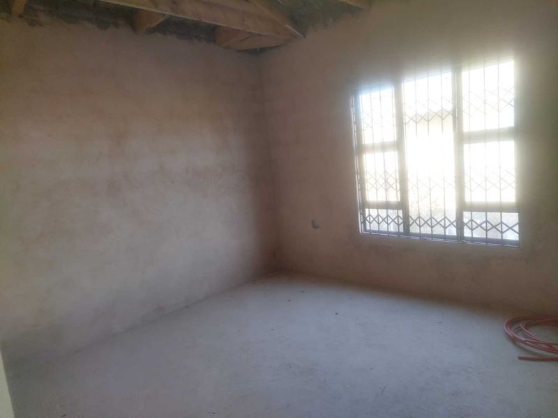 An unfinished bedroom space featuring exposed timber rafters and plaster walls, awaiting final finishes and flooring.
