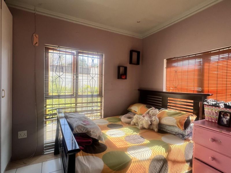 A bedroom featuring built-in wardrobes, tiled flooring, and security bars on the windows, providing a functional and secure living space.