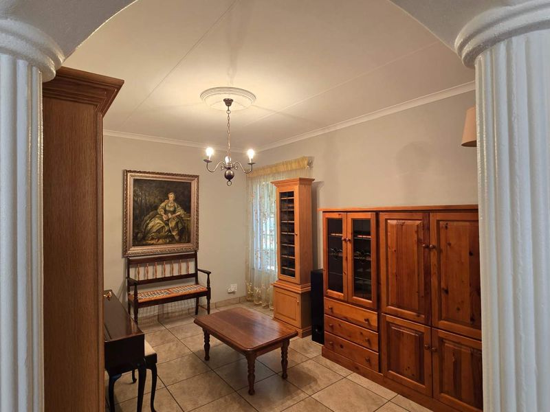 A living area featuring tiled flooring, a decorative ceiling rose, and classic architectural columns framing the entrance.