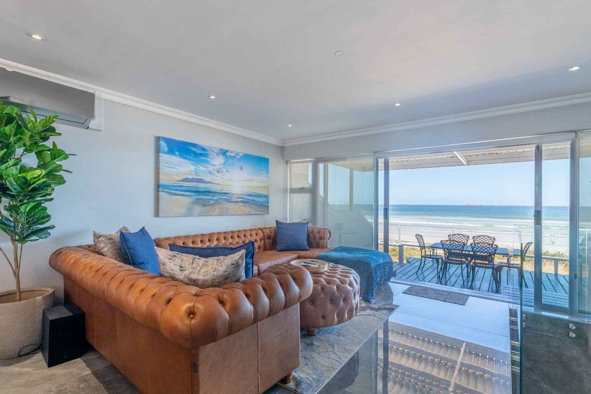 Spacious living room featuring tiled floors, recessed lighting, and large sliding glass doors that open onto a balcony with direct ocean views.