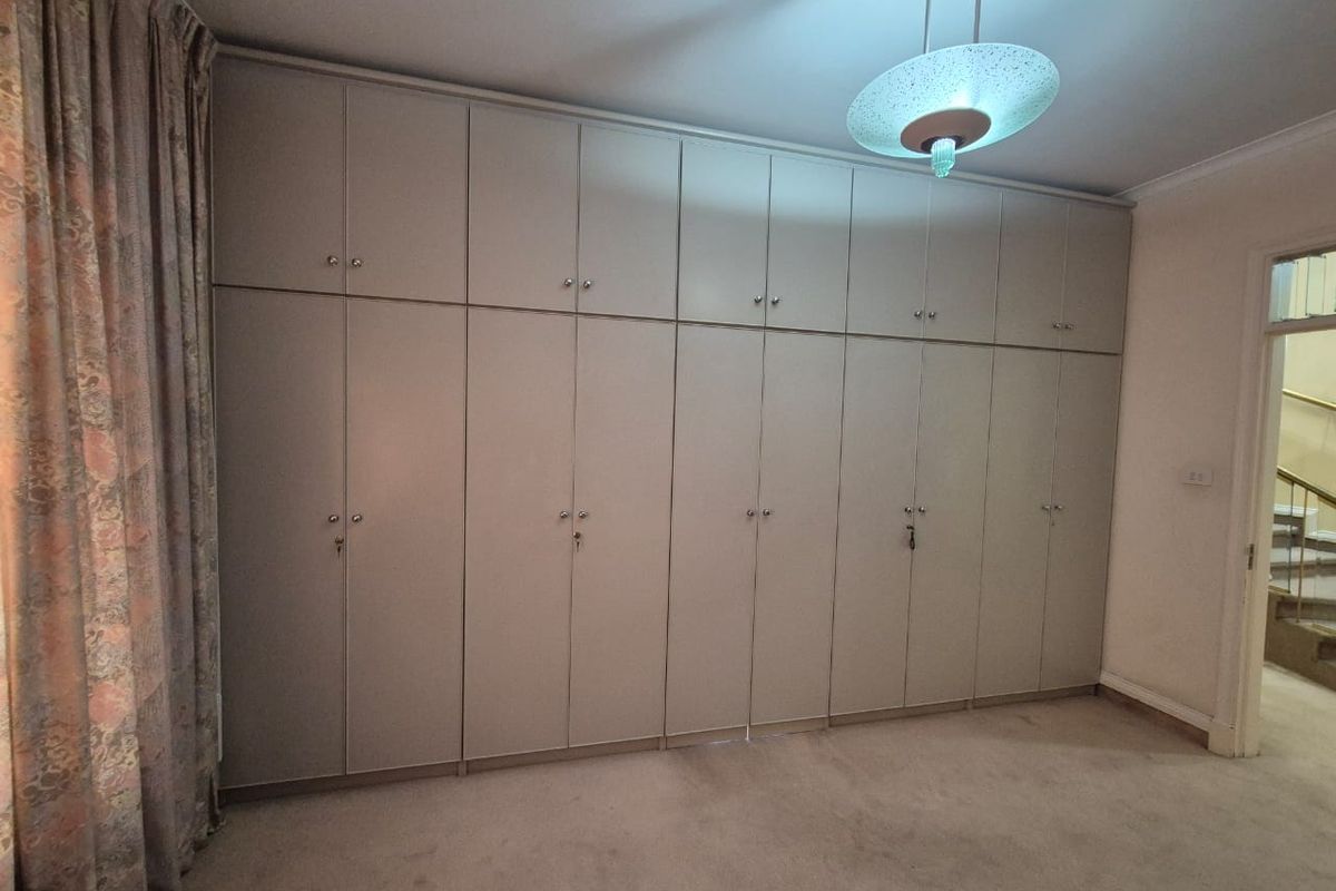 A bedroom featuring extensive floor-to-ceiling built-in cupboards providing ample storage space.