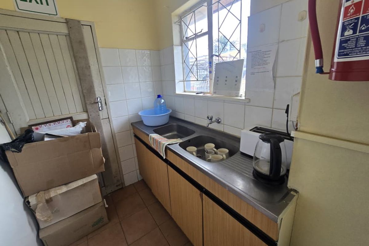 A functional kitchenette area featuring a stainless steel double sink, tiled splashback, and built-in wooden cabinetry.