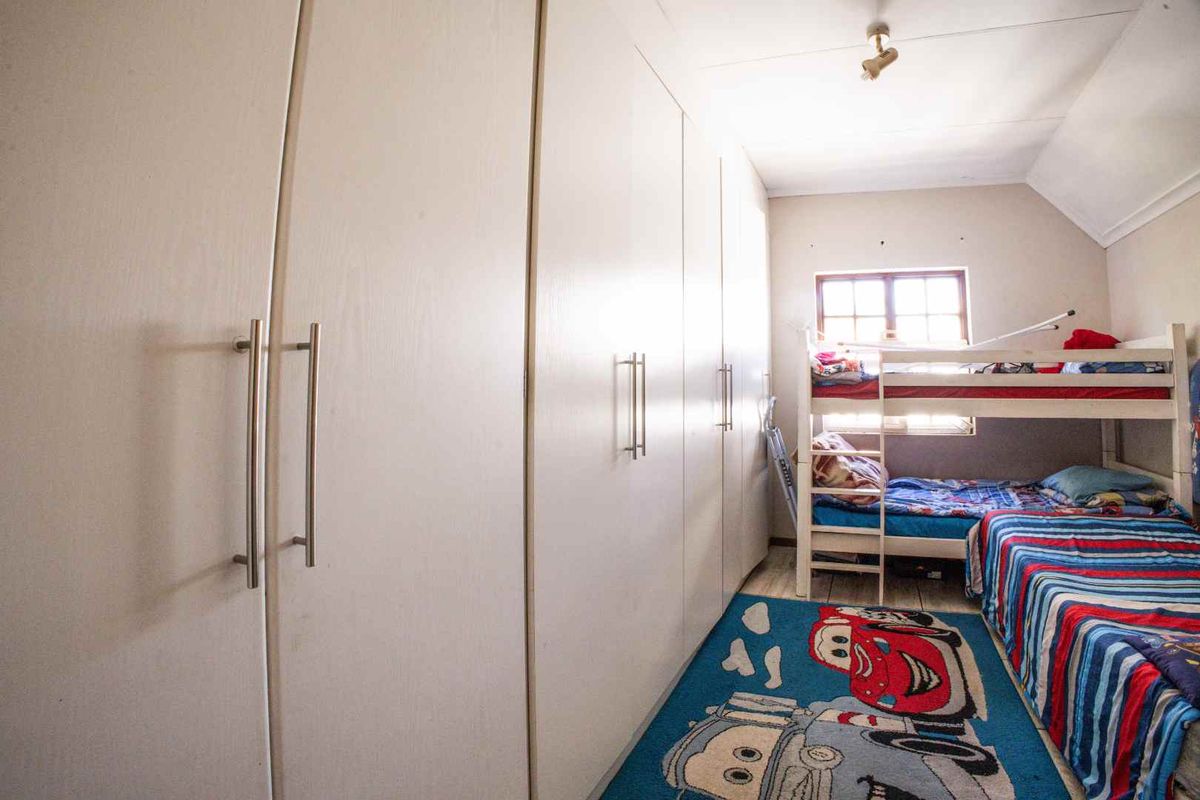 A bedroom featuring extensive built-in cupboards and a sloped ceiling, providing functional storage space.