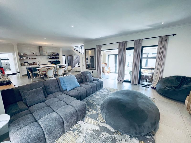 Spacious open-plan living area featuring a modern kitchen with island, tiled floors, and large sliding doors leading to the outdoor patio.