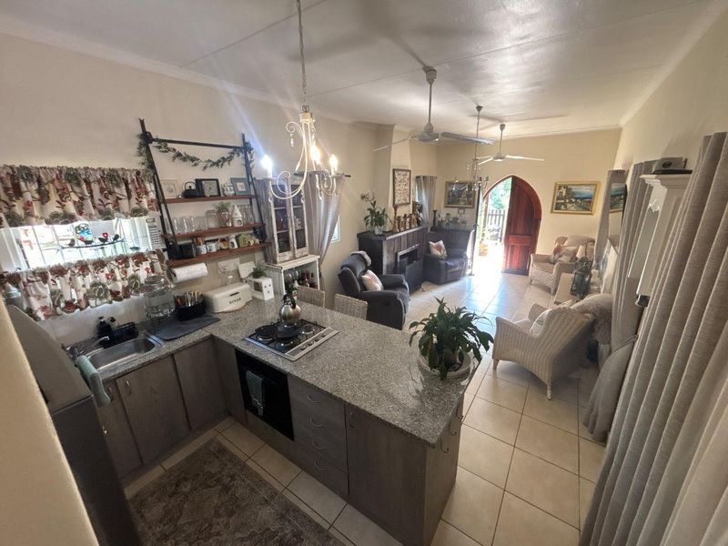 Open-plan living area featuring a kitchen with granite countertops, built-in oven, gas hob, and tiled flooring, leading to an arched exterior entrance.