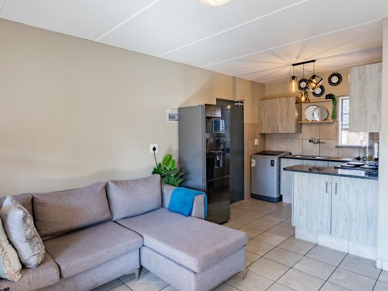 An open-plan living area featuring a functional kitchen with modern cabinetry, granite countertops, and tiled flooring throughout the space.