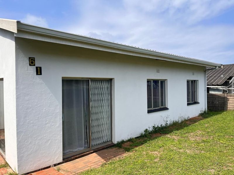 Rear exterior view of the property featuring white painted walls, sliding glass doors with security gates, and aluminium window frames.