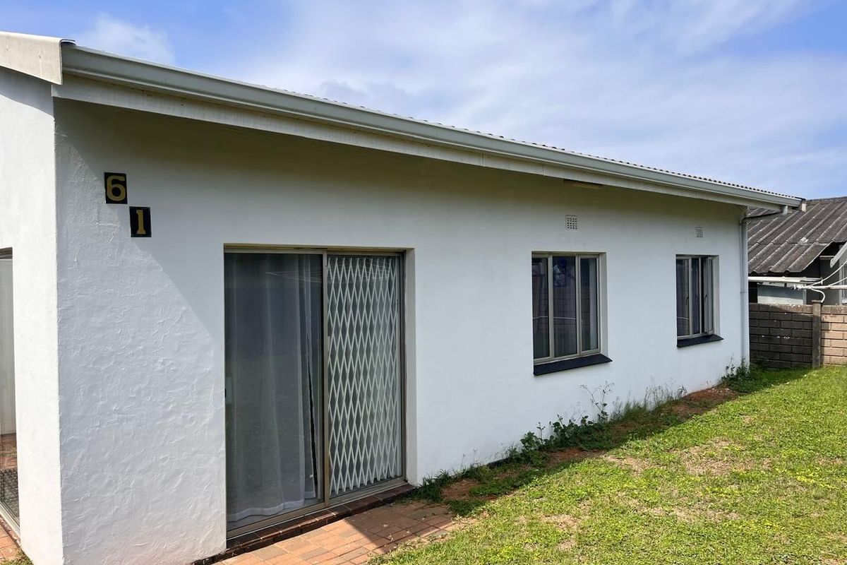 Rear exterior view of the property featuring white painted walls, sliding glass doors with security gates, and aluminium window frames.