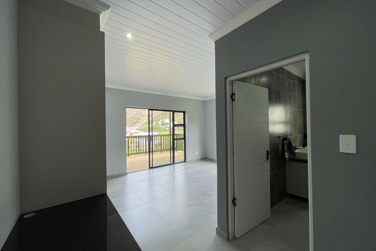 Bright and spacious living area featuring neutral tiled floors, a modern tongue and groove ceiling, and sliding doors leading to an outdoor deck.