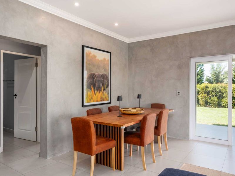 A bright dining room featuring modern plastered walls, tiled flooring, and a sliding glass door providing direct access to the garden.