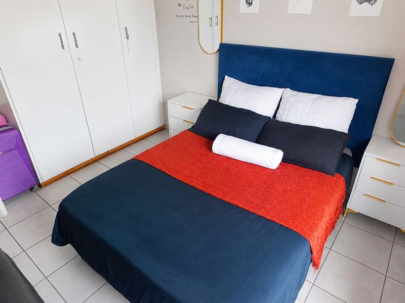A well-maintained bedroom featuring neutral tiled flooring and practical built-in cupboards, providing ample storage space.