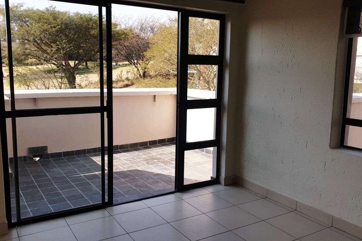 Bright living area featuring neutral tiled flooring and large sliding glass doors opening onto a private balcony with scenic views.