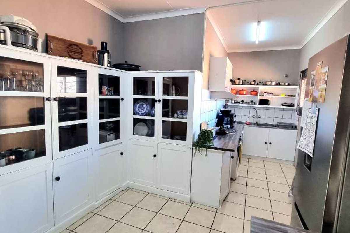 A functional kitchen featuring white cabinetry, tiled flooring, and a dedicated prep area with integrated storage solutions.