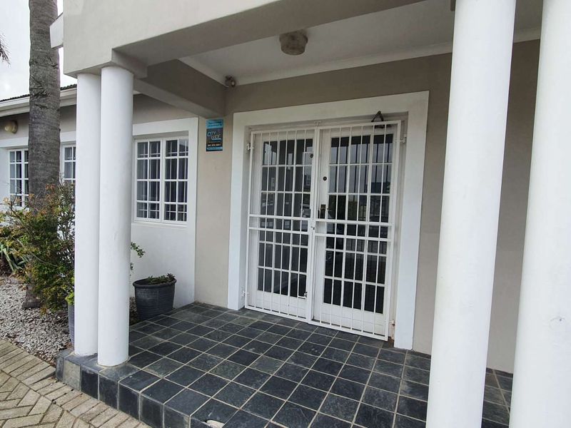 Front entrance of the office building featuring a covered porch with tiled flooring, structural columns, and security gates.