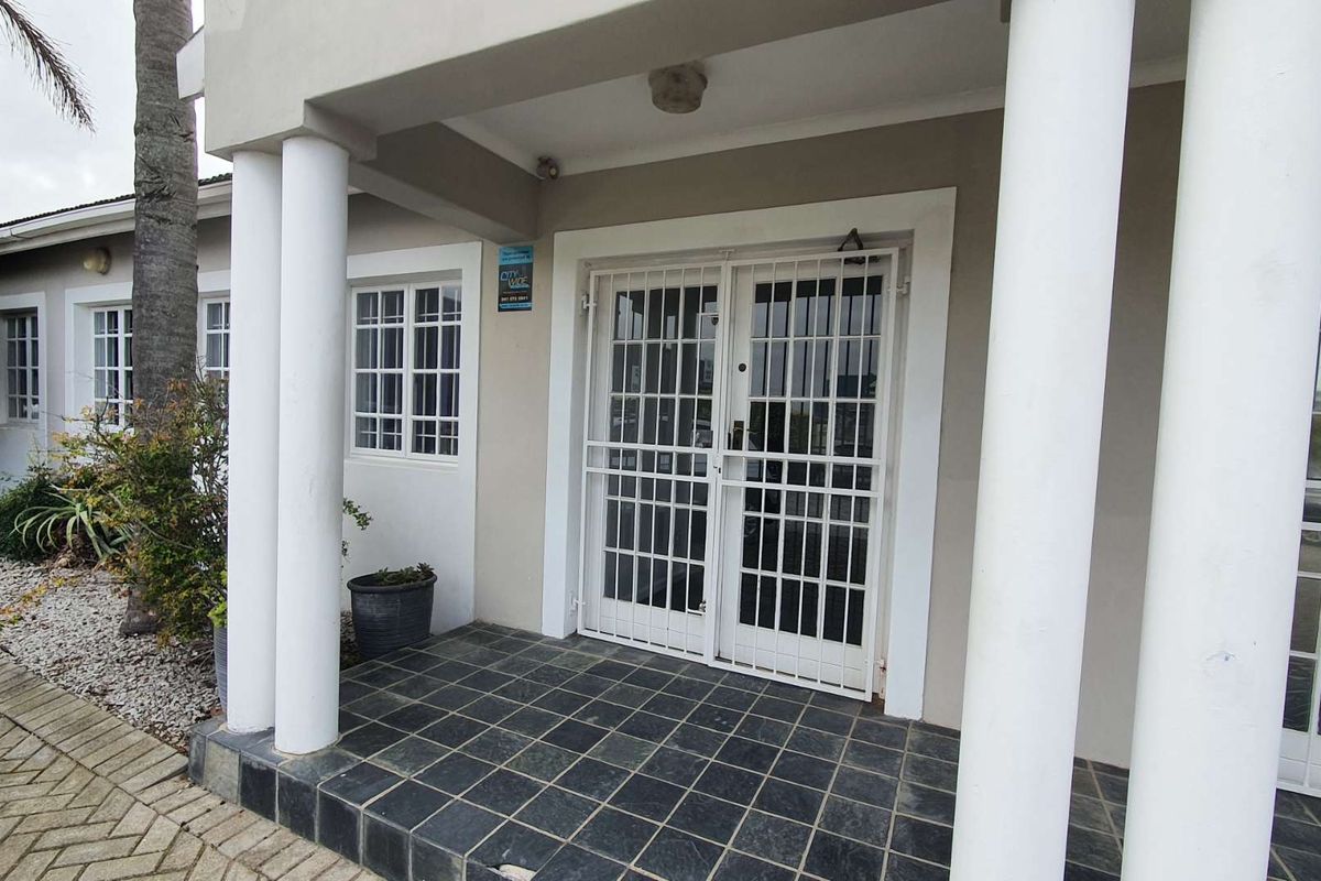 Front entrance of the office building featuring a covered porch with tiled flooring, structural columns, and security gates.