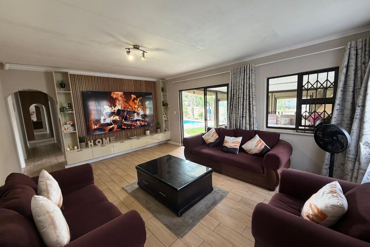 Spacious living room featuring a modern built-in media wall, tiled flooring, and large sliding doors providing natural light and access to the outdoor area.