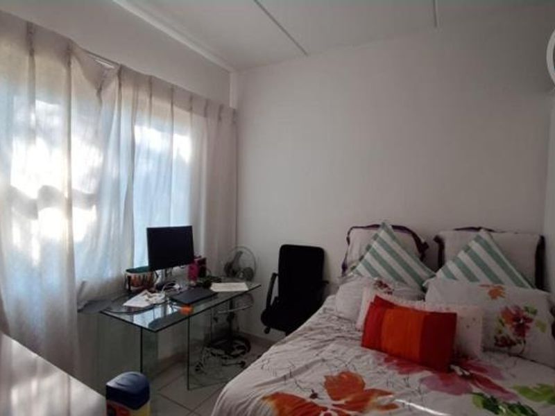 A functional bedroom featuring built-in wardrobes and tiled flooring, offering a practical layout with natural light from the window.