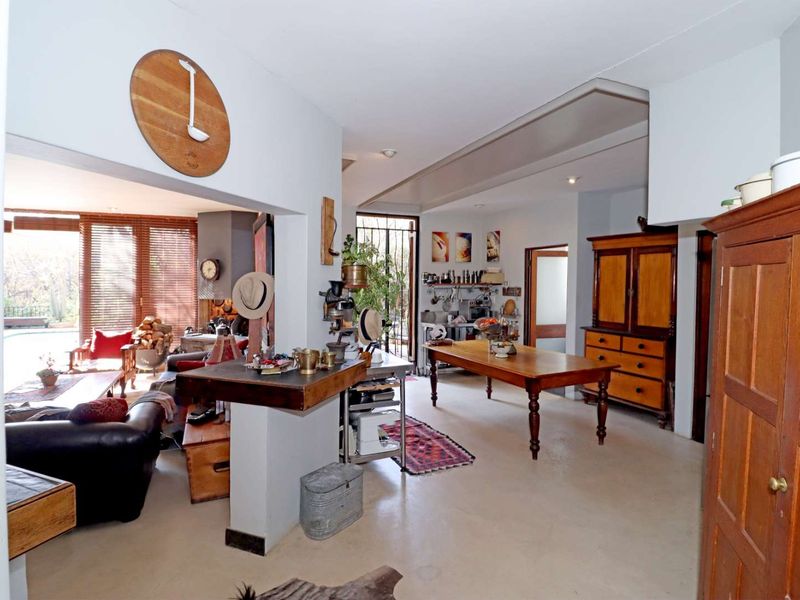 Spacious open-plan living area featuring a central fireplace, neutral concrete flooring, and seamless flow between the lounge and dining spaces.