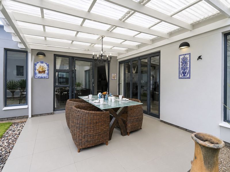 A well-maintained covered patio featuring tiled flooring, a translucent roof, and bi-fold doors providing seamless access to the interior living spaces.