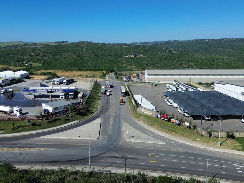 Aerial view of an industrial precinct featuring a truck stop, warehouse facilities, and extensive paved parking areas with shade structures.