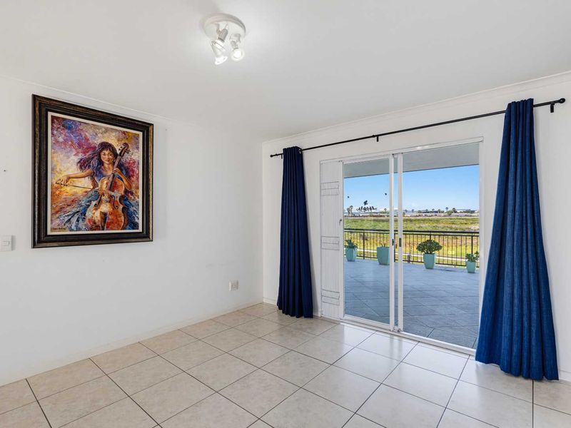 Bright and spacious living area featuring neutral tiled flooring and large sliding glass doors leading to an outdoor balcony with scenic views.