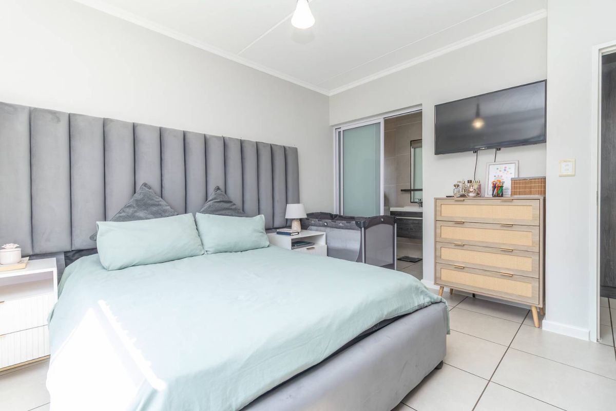 A well-maintained bedroom featuring tiled flooring, a neutral color palette, and direct access to an en-suite bathroom through a sliding door.
