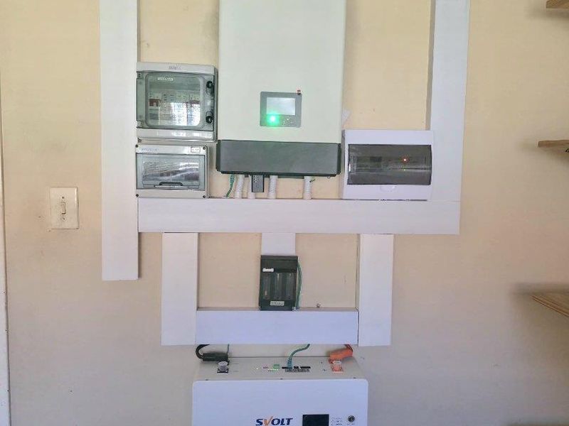 A wall-mounted solar power system featuring a Luxpower inverter and Svolt battery storage unit, neatly installed in a utility area.