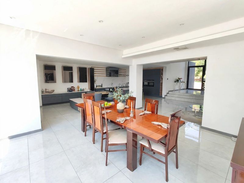 Spacious open-plan living and dining area featuring modern tiled floors, recessed lighting, and a sleek, contemporary kitchen with integrated appliances.