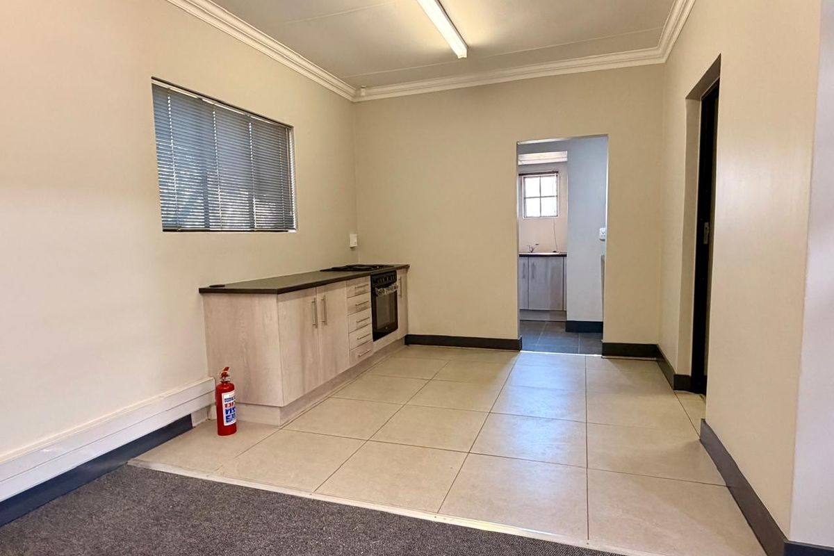A functional kitchen area featuring built-in cabinetry, an integrated oven and hob, tiled flooring, and a view through to an adjacent utility space.