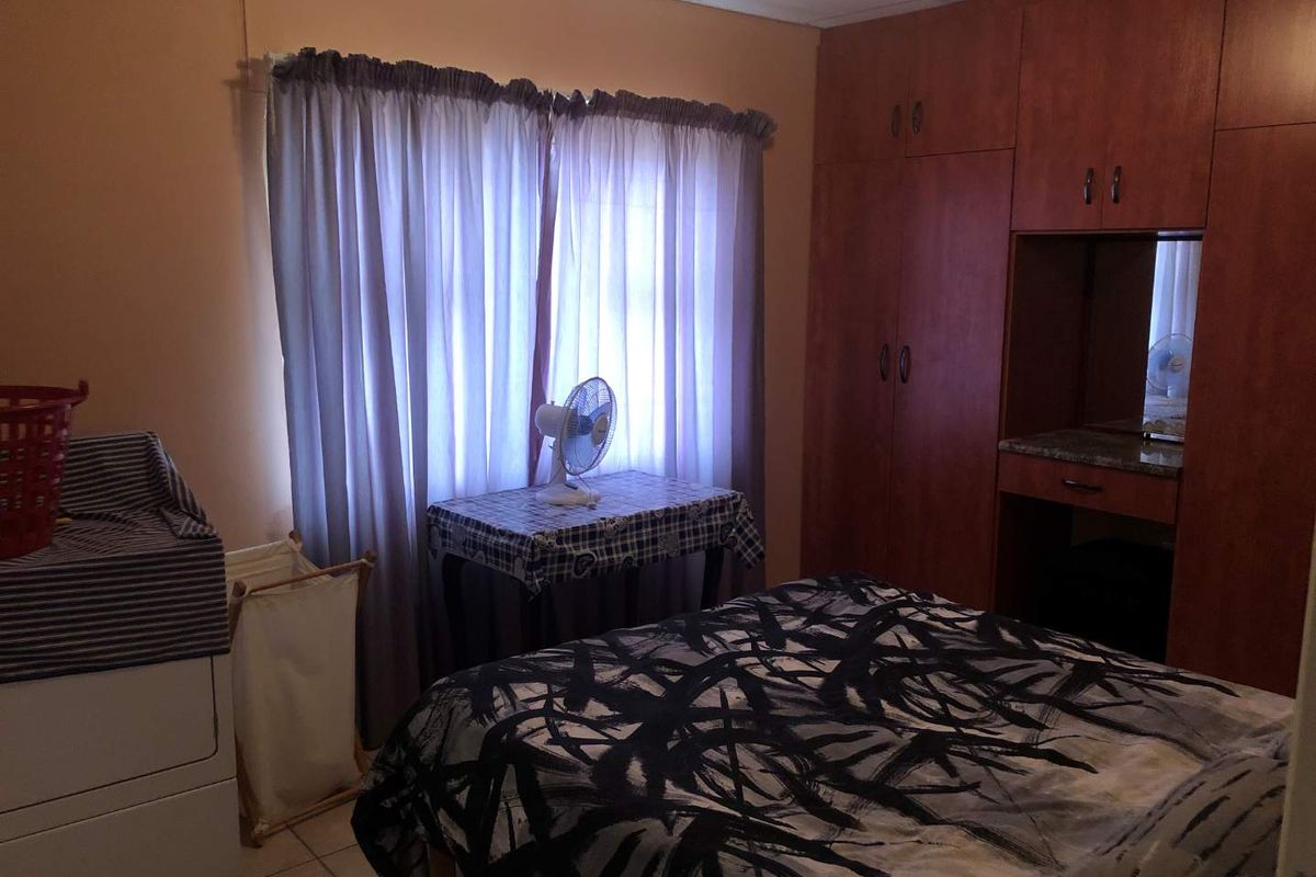 A bedroom featuring built-in wooden cabinetry with an integrated vanity and tiled flooring.