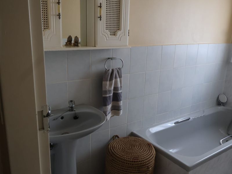A functional bathroom featuring a pedestal basin, bathtub, and wall-mounted medicine cabinet with tiled splashback finishes.