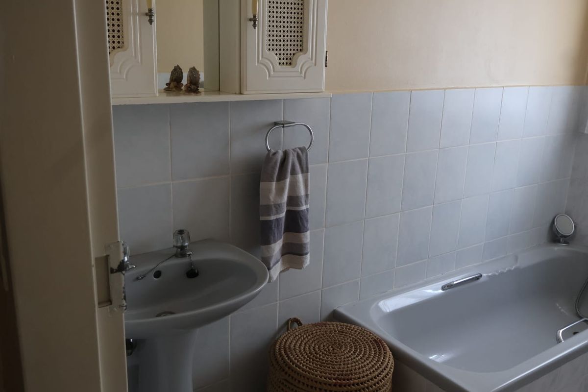 A functional bathroom featuring a pedestal basin, bathtub, and wall-mounted medicine cabinet with tiled splashback finishes.