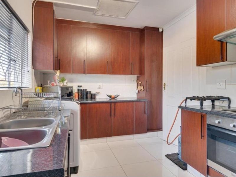 Functional kitchen featuring dark wood cabinetry, granite-look countertops, a gas hob with built-in oven, and tiled flooring.