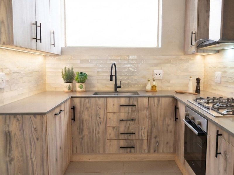 Modern kitchen featuring wood-grain cabinetry, stone countertops, a gas hob, built-in oven, and stylish tiled backsplash with integrated under-cabinet lighting.