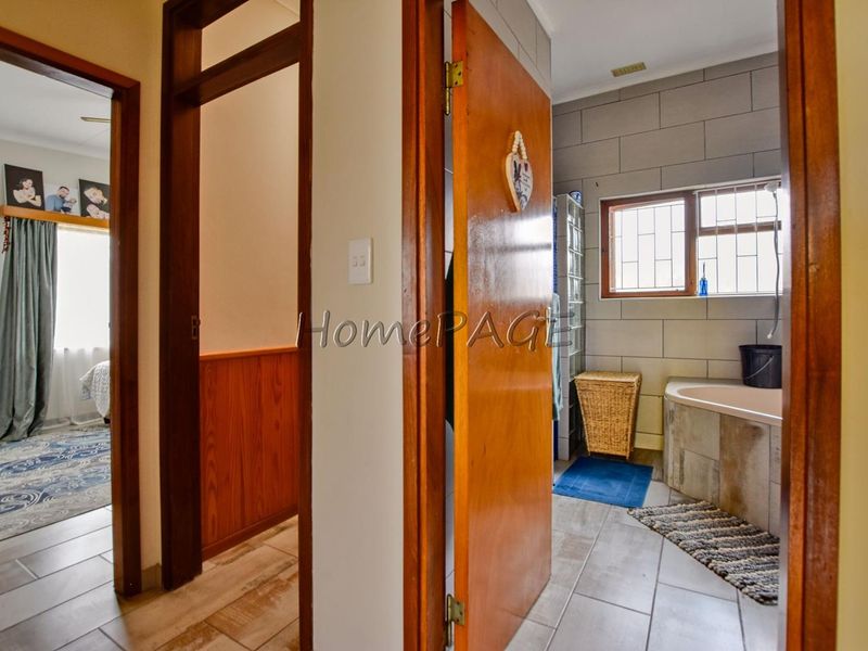 A hallway view showing access to a bedroom and a bathroom featuring a built-in bathtub and tiled finishes.