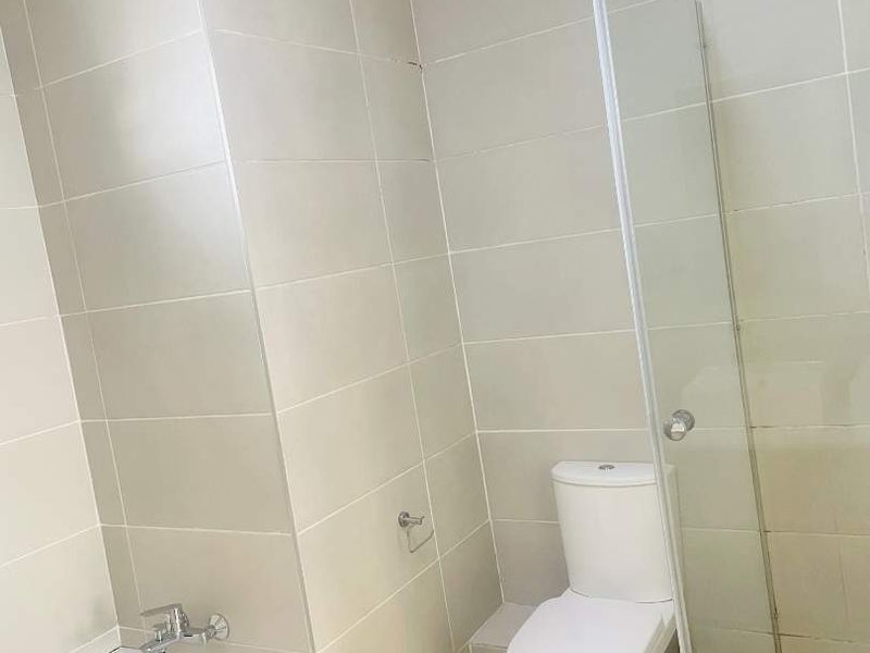A functional bathroom featuring a built-in bathtub, separate shower enclosure, and toilet with neutral wall and floor tiling.