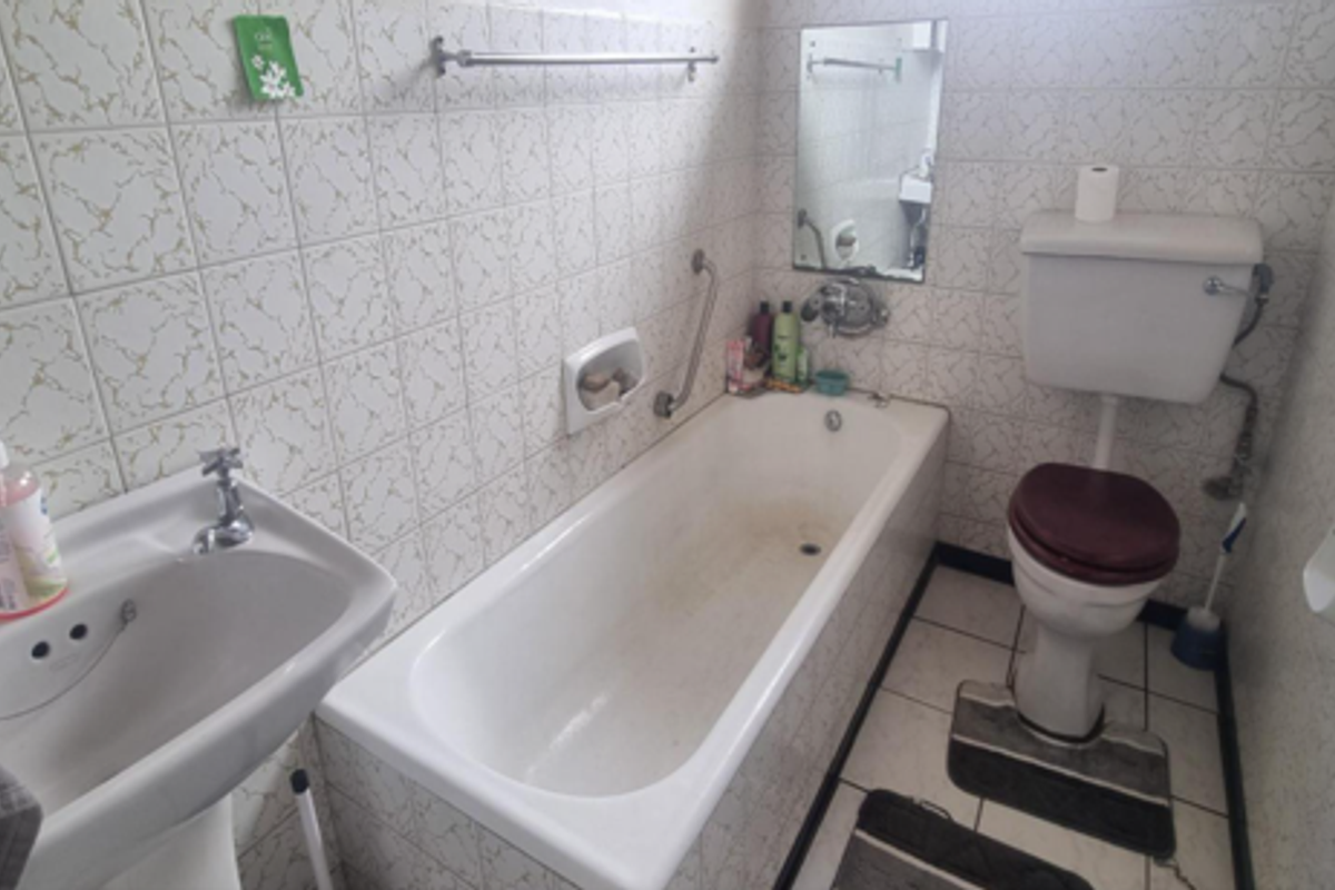 A dated bathroom featuring a pedestal basin, bathtub, and toilet with original ceramic wall tiling, requiring modernization to improve aesthetic appeal and functionality.