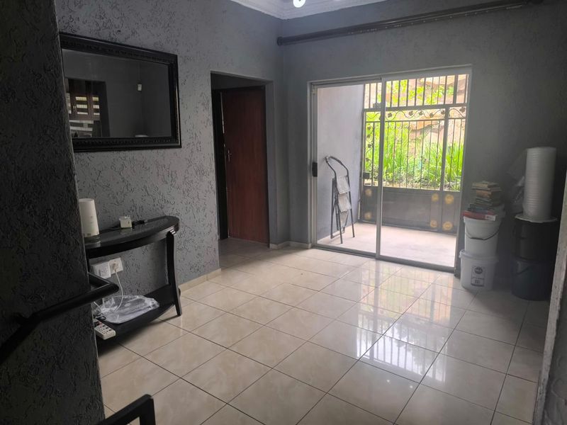 A bright, open living area featuring tiled floors, textured grey walls, and a sliding glass door providing direct access to the outdoor space.