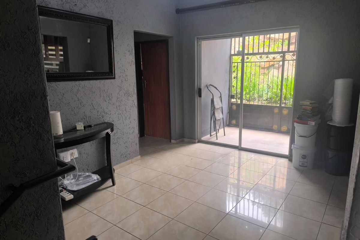 A bright, open living area featuring tiled floors, textured grey walls, and a sliding glass door providing direct access to the outdoor space.