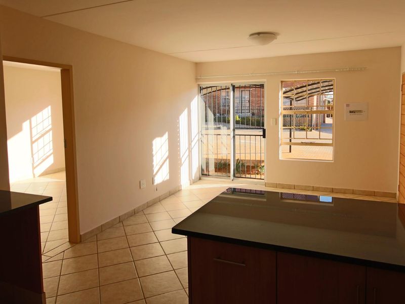 An open-plan living and kitchen area featuring tiled floors, granite countertops, and direct access to an outdoor space through a sliding glass door.