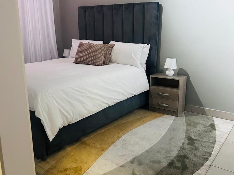 A well-maintained bedroom featuring neutral wall tones, tiled flooring, and a modern curtain installation.