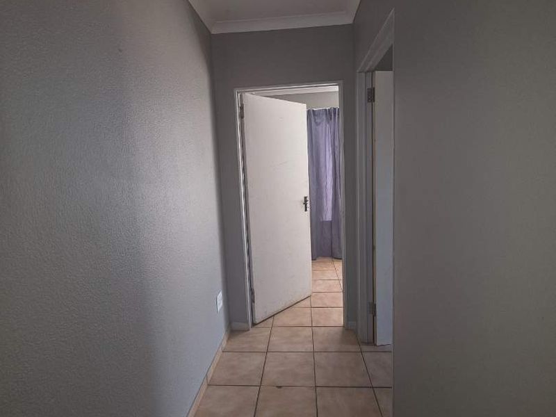 A functional hallway featuring neutral grey walls and ceramic floor tiles, providing access to adjacent rooms.