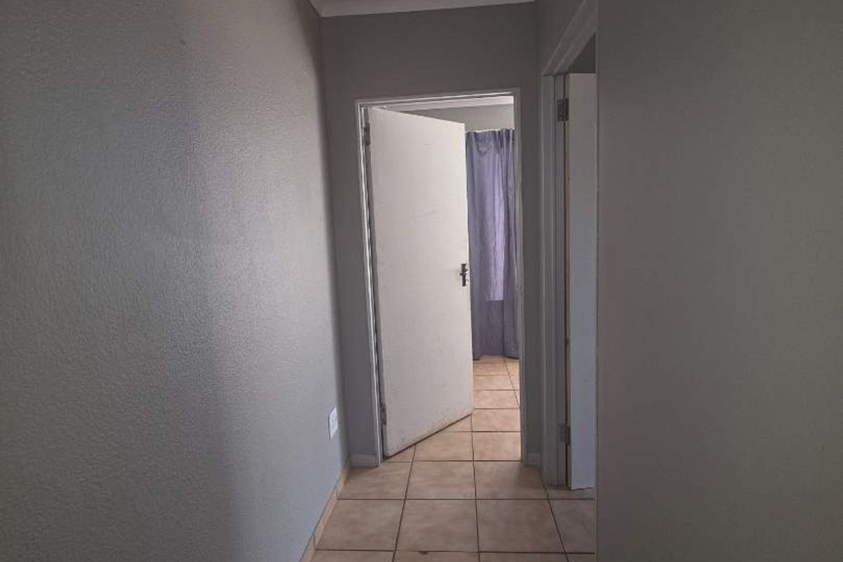 A functional hallway featuring neutral grey walls and ceramic floor tiles, providing access to adjacent rooms.